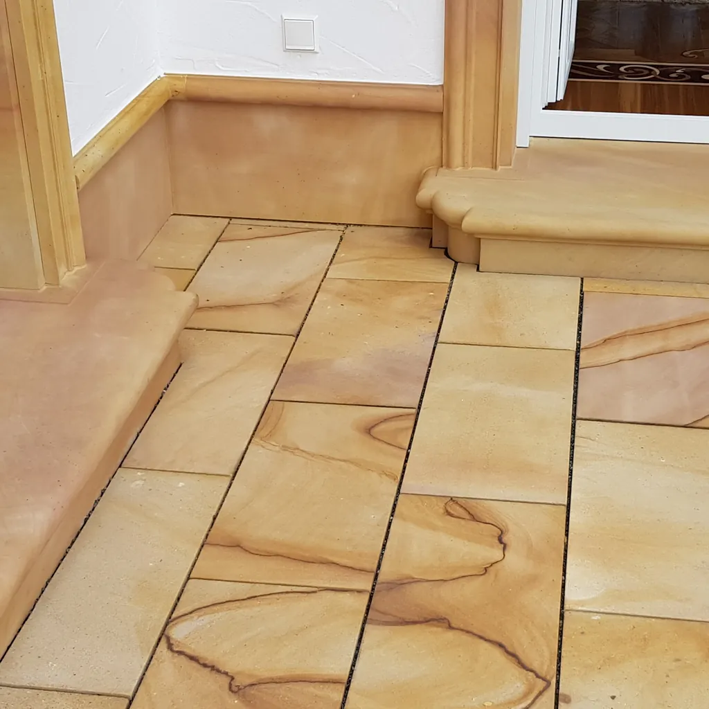 Gelber Sandstein-Terrassenplatten mit ausgeprägter Maserung im Innenbereich, daneben profilierte Sandstein-Türschwelle und Türeinfassung