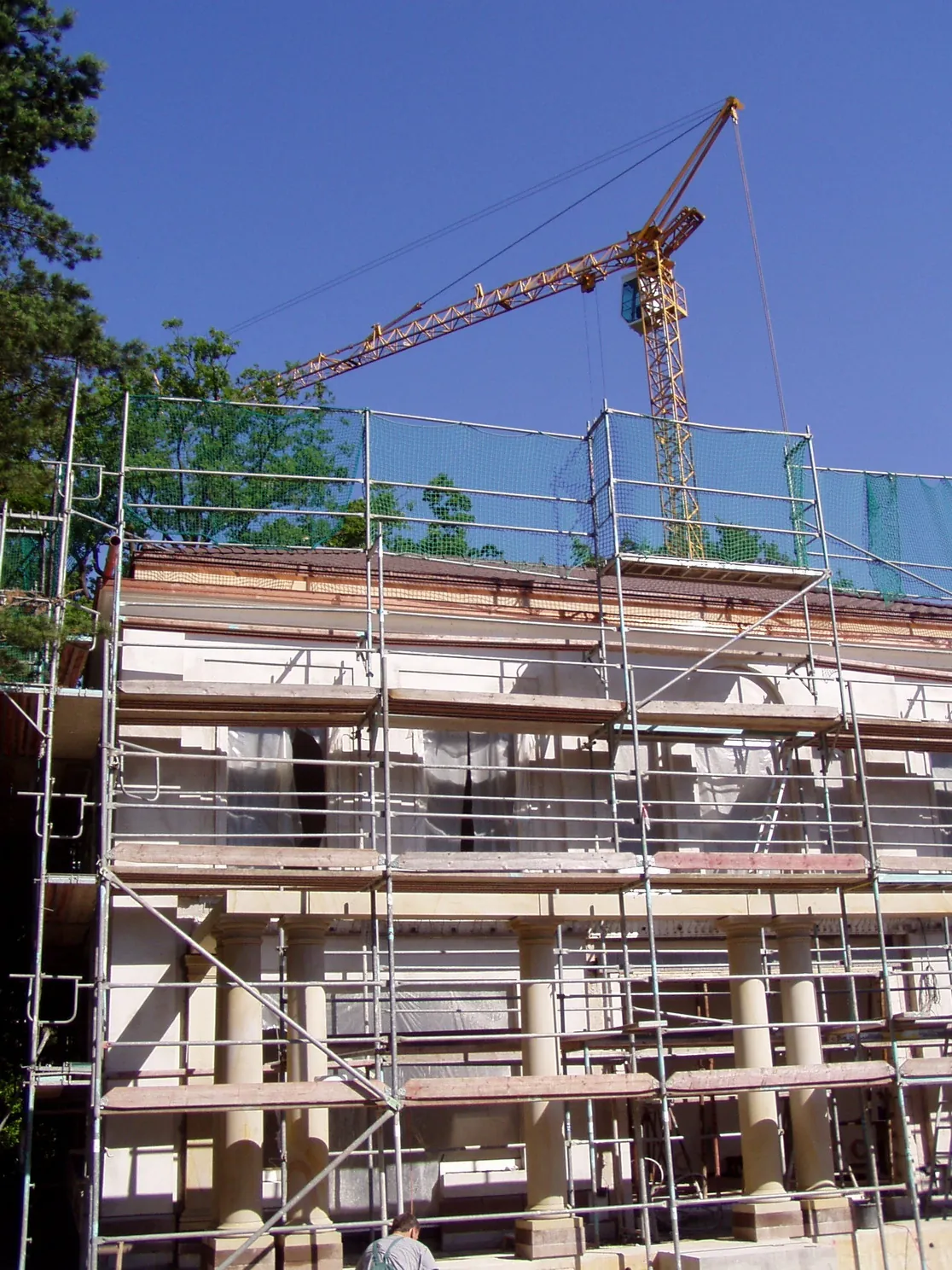Sandstein-Villenfassade im Bau mit Gerüst, sichtbaren Sandstein-Säulen und Gesimsen im Rohbauzustand, Baukran im Hintergrund