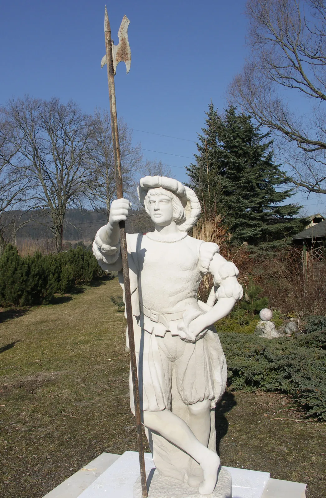 Lebensgroße Sandstein-Ritterfigur mit Hellebarde auf quadratischem Sockel – handgemeißelte Gartenskulptur aus hellem Sandstein