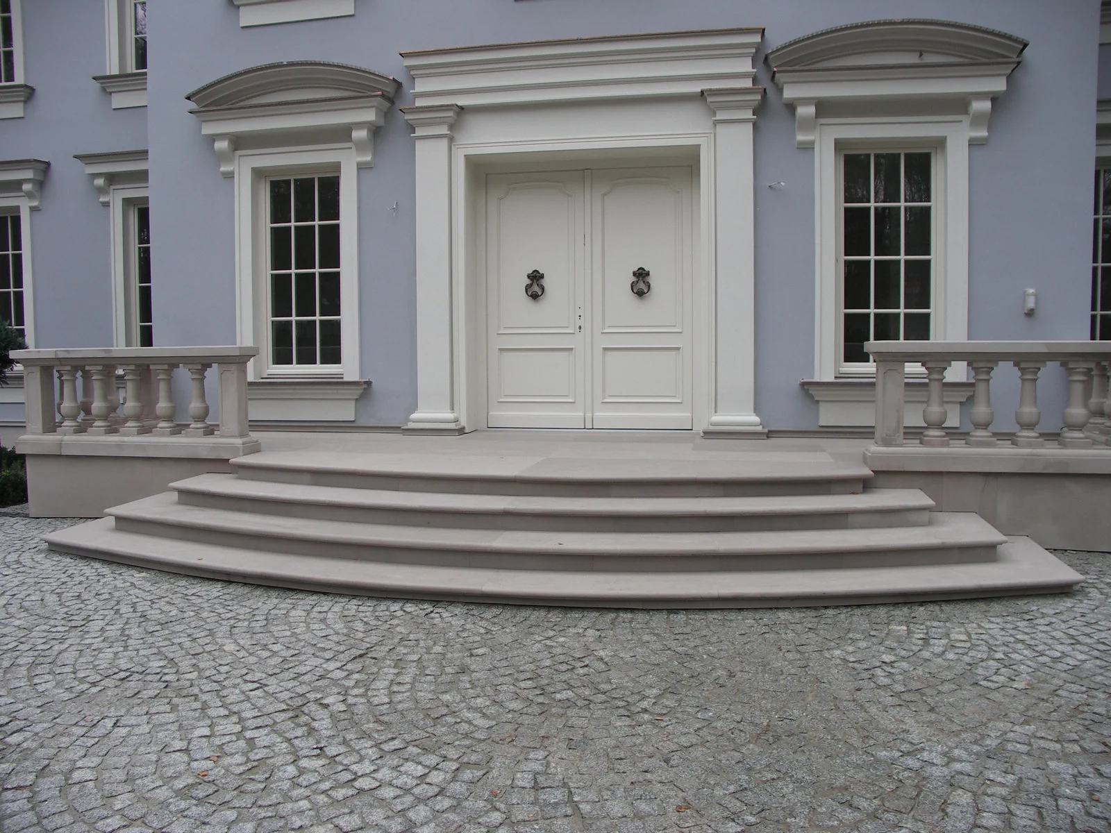 Helle Sandstein-Freitreppe mit halbrunden Treppenstufen, klassischer Balustrade und Sandstein-Fenstereinfassungen mit Bogensturz an Villenfassade