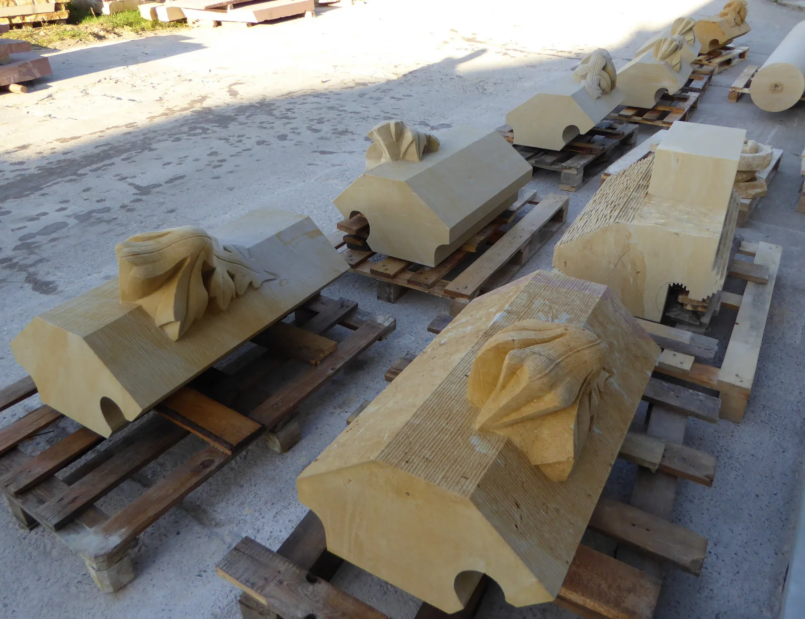 Niederschlesischer Sandstein-Gesimse mit CNC-gefrästen Akanthusreliefs auf Lagerpaletten – Serienvorfertigung figurativer Werkstein-Elemente im Außenlager
