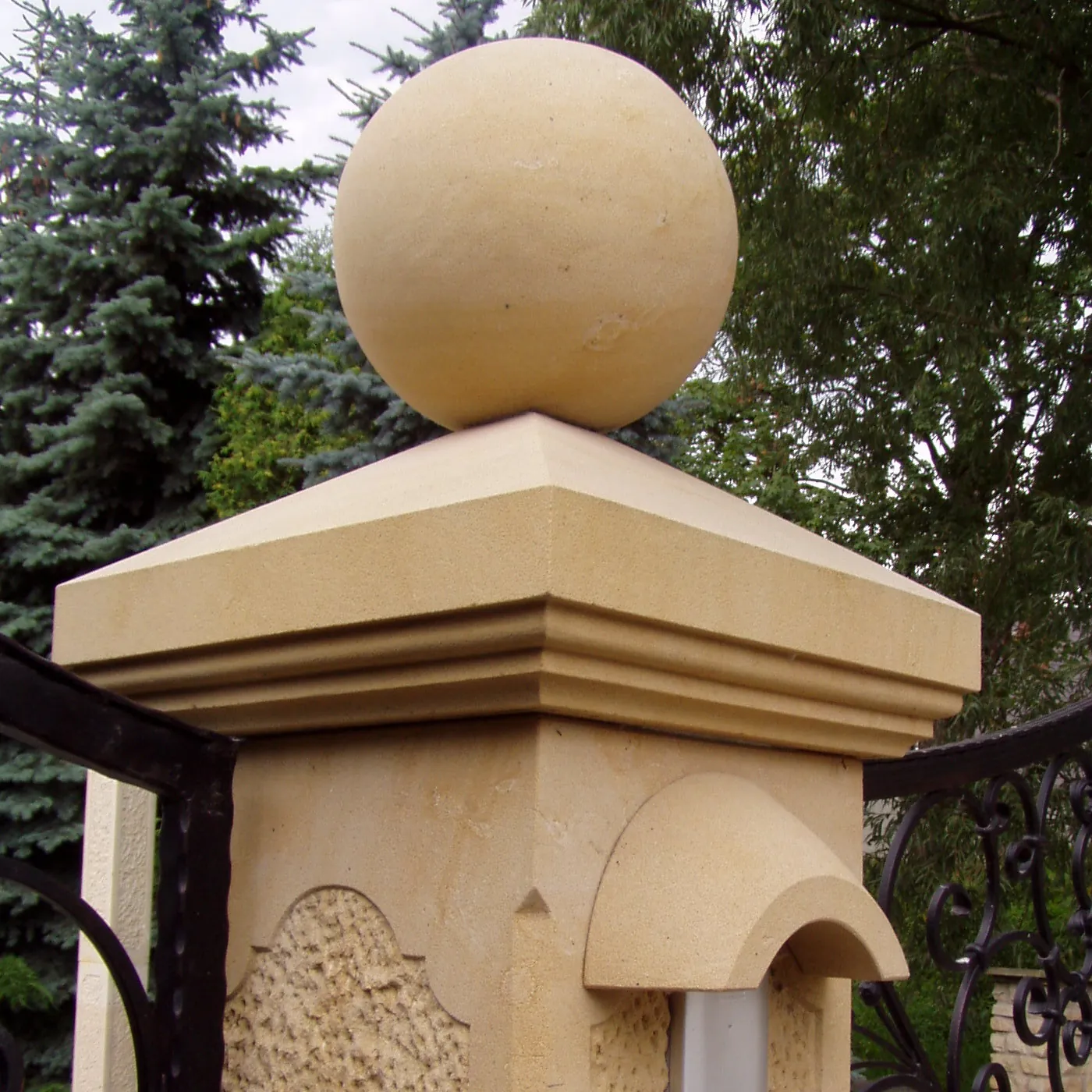 Gelber Sandstein-Torpfeiler mit profilierter Abdeckplatte und gedrechselter Sandsteinkugel als Aufsatz, flankiert von schmiedeeisernem Tor