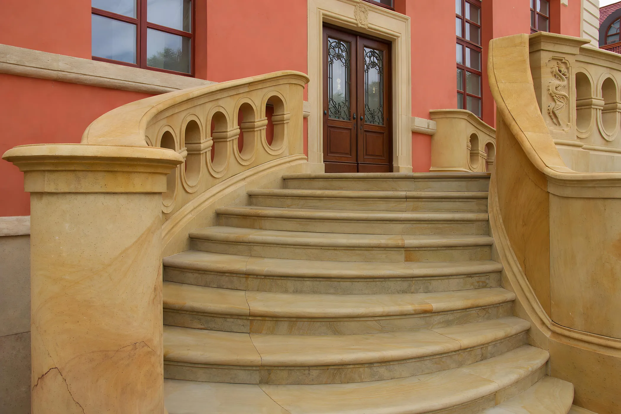 Geschwungene Freitreppe aus gelbem Sandstein mit Balustrade und Rundpfeilern am Hauseingang