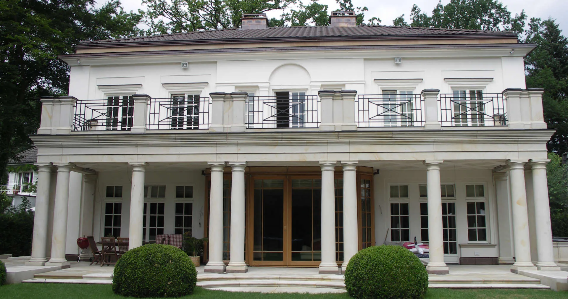 Fassadenansicht der Villa mit Säulen und Balustradenpfeilern aus heller Sandstein