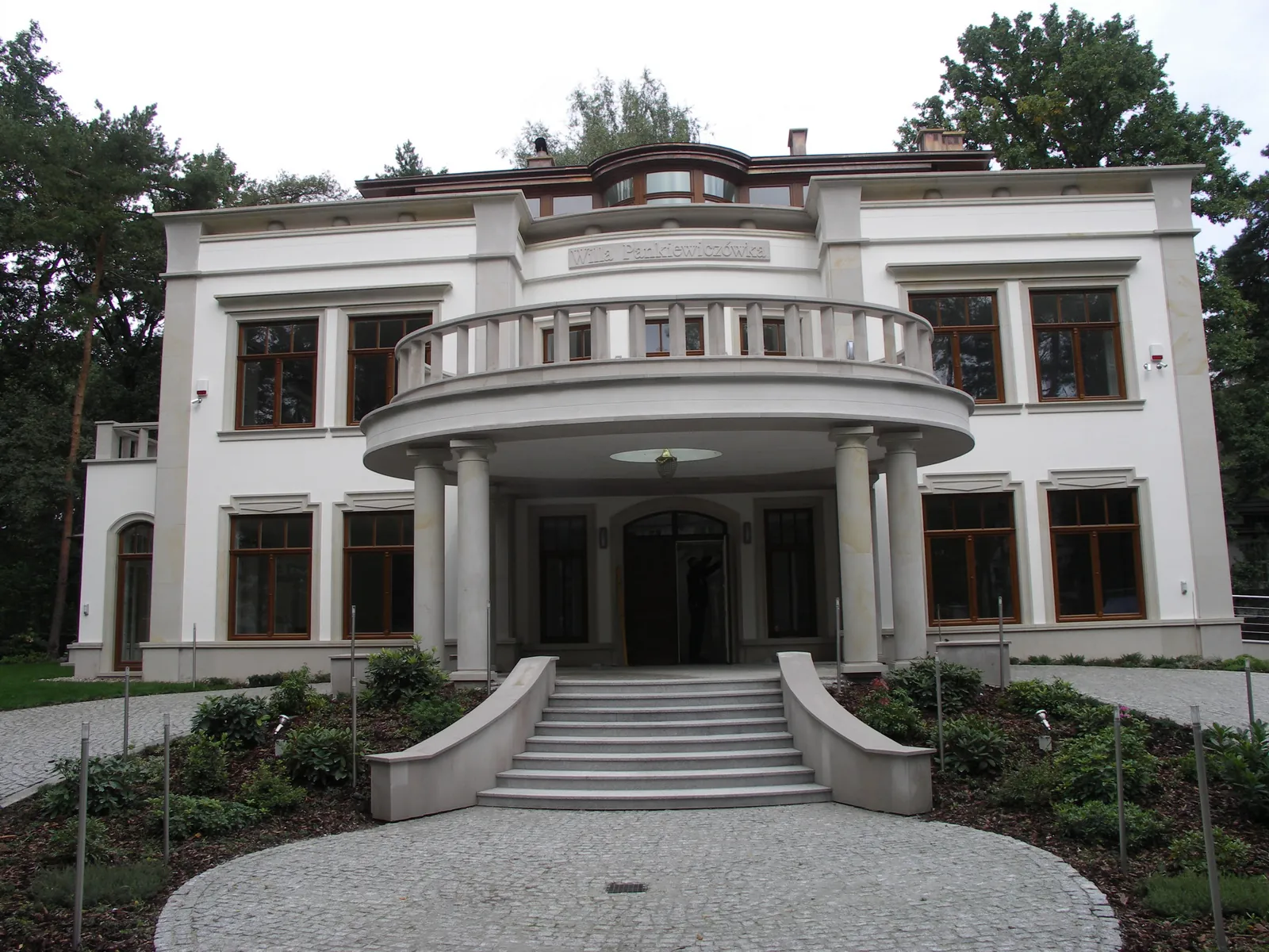 Repräsentative Villenfassade aus hellem Sandstein mit Säulen.